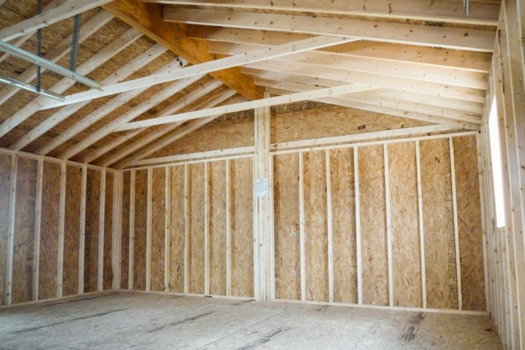 Interior of a partially constructed room featuring wooden beams and OSB walls, with an open, spacious feel and natural light.