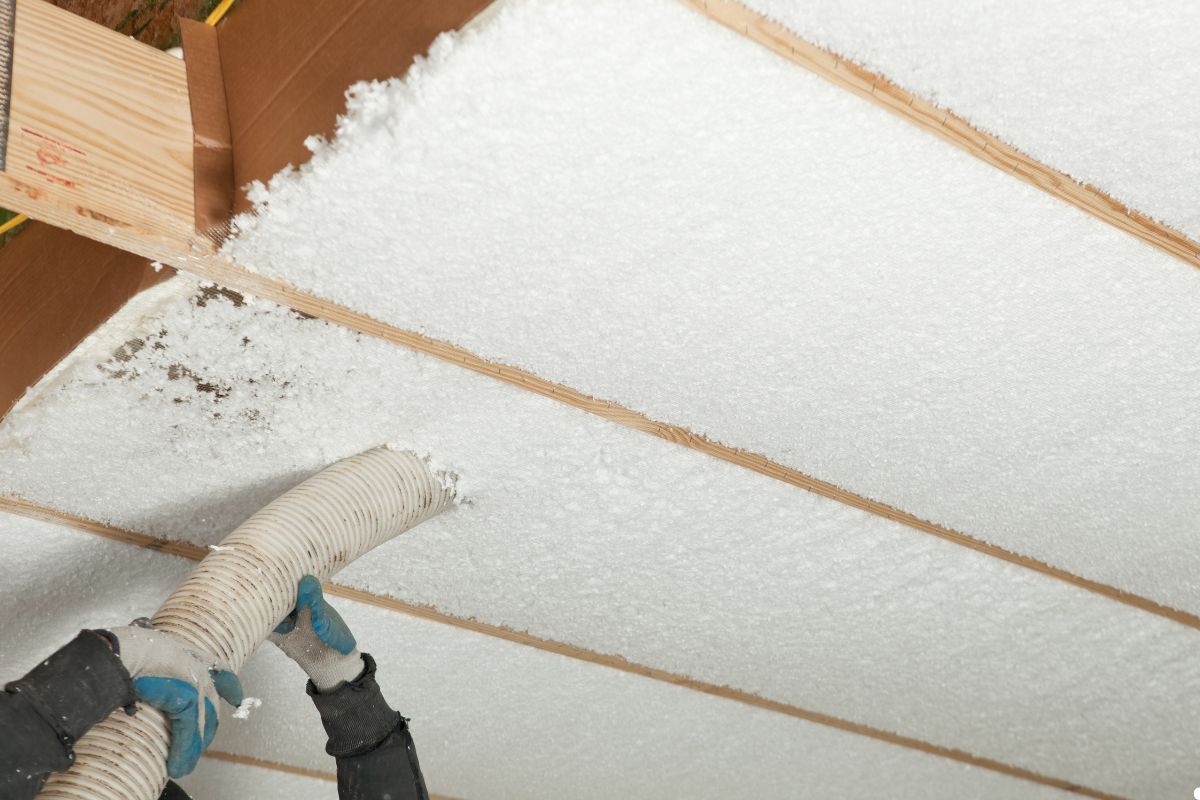 A person using a vacuum cleaner to remove dust from the ceiling in a well-lit room.